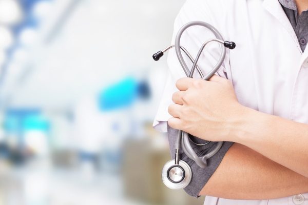 Doctor with a stethoscope in the hands and hospital background.